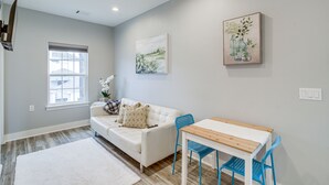 Een moderne woonkamer met een witte bank, een houten eettafel en blauwe stoelen.