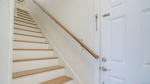 Een trap met houten treden en een leuning, leidend naar een witte deur met een zilveren handvat.