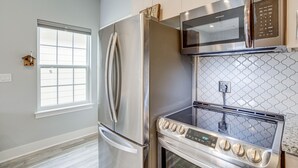 Een moderne keuken met roestvrijstalen apparatuur, waaronder een koelkast, magnetron en oven.