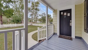 A porch with a white railing, a black door with a welcome mat, and a pathway leading to a white picket fence. - Dtwn St Marys Home Near Waterfront: Pets Welcome! (St. Marys)