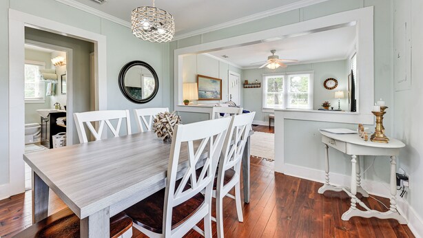 A dining area with a wooden table, white chairs, and a chandelier. There is a mirror on the wall and a ceiling fan in the background. - Dtwn St Marys Home Near Waterfront: Pets Welcome! (St. Marys)
