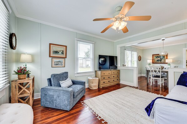 A spacious living room with a blue sofa, wooden coffee table, and a ceiling fan.