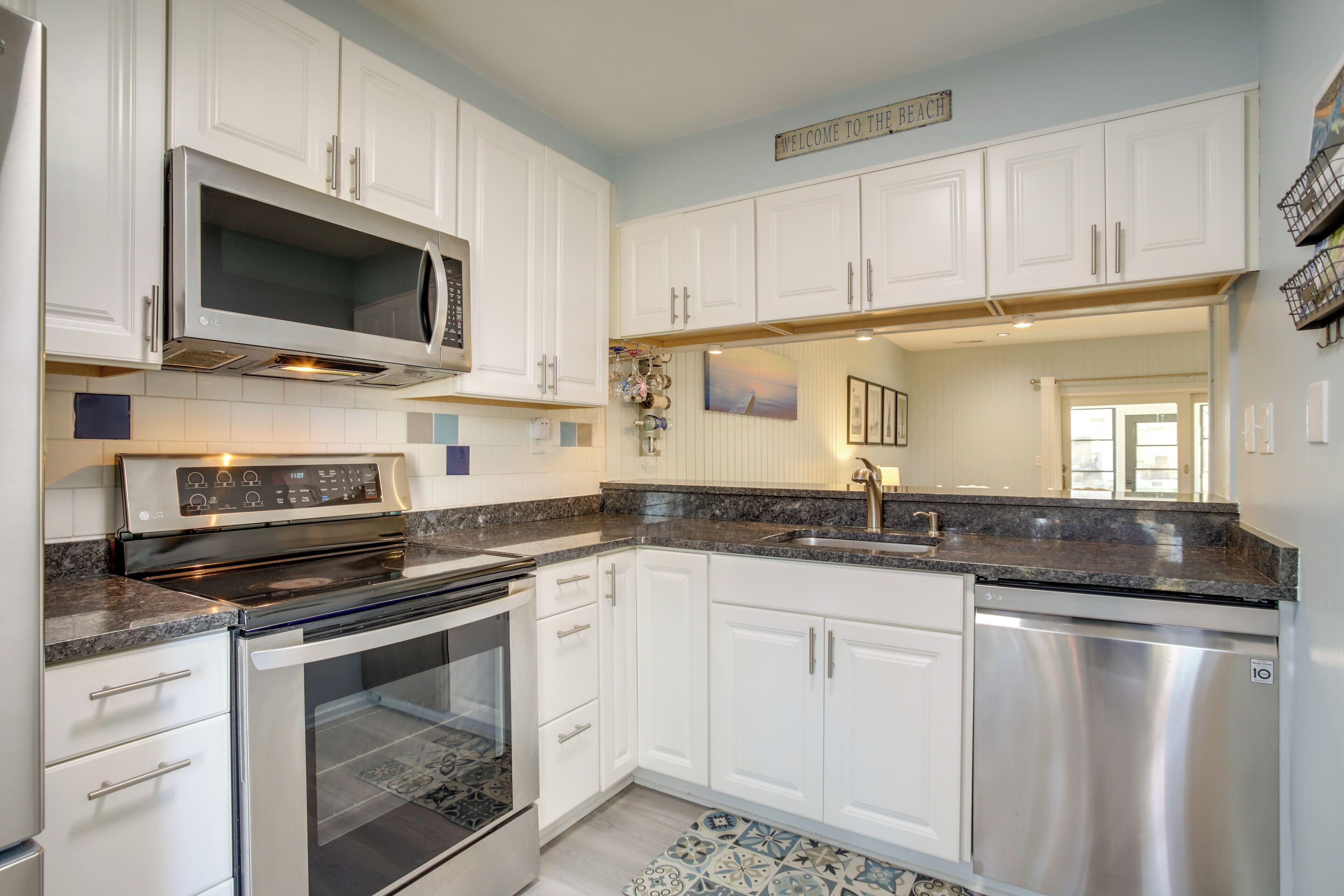 A modern kitchen with white cabinetry, stainless steel appliances, and a granite countertop.