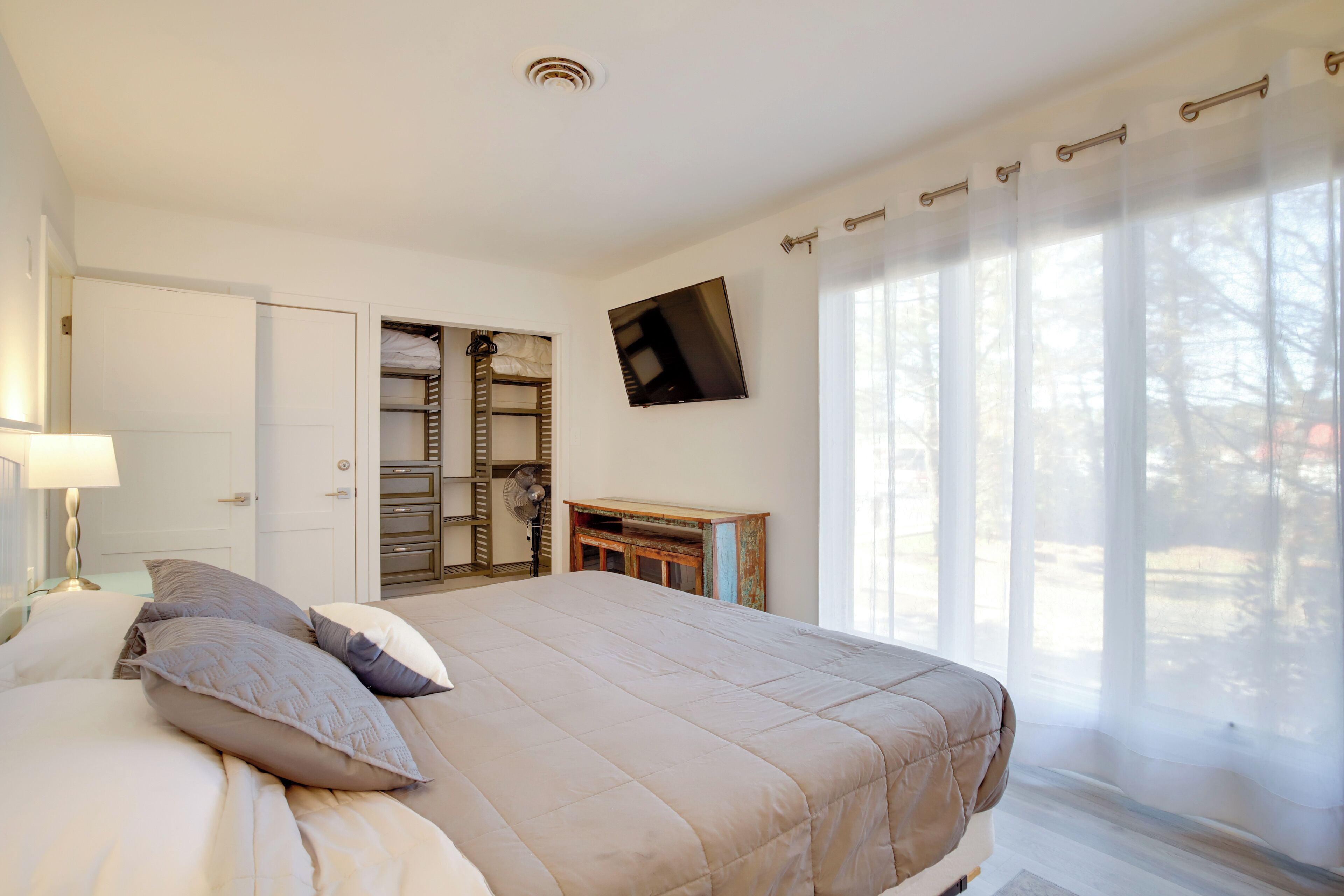 Ein Schlafzimmer mit einem Bett, einem Fernseher, einem Kleiderschrank und einem Fenster mit Vorhängen.