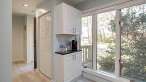 Une cuisine avec des meubles blancs, un plan de travail noir et une fenêtre donnant sur un paysage verdoyant.