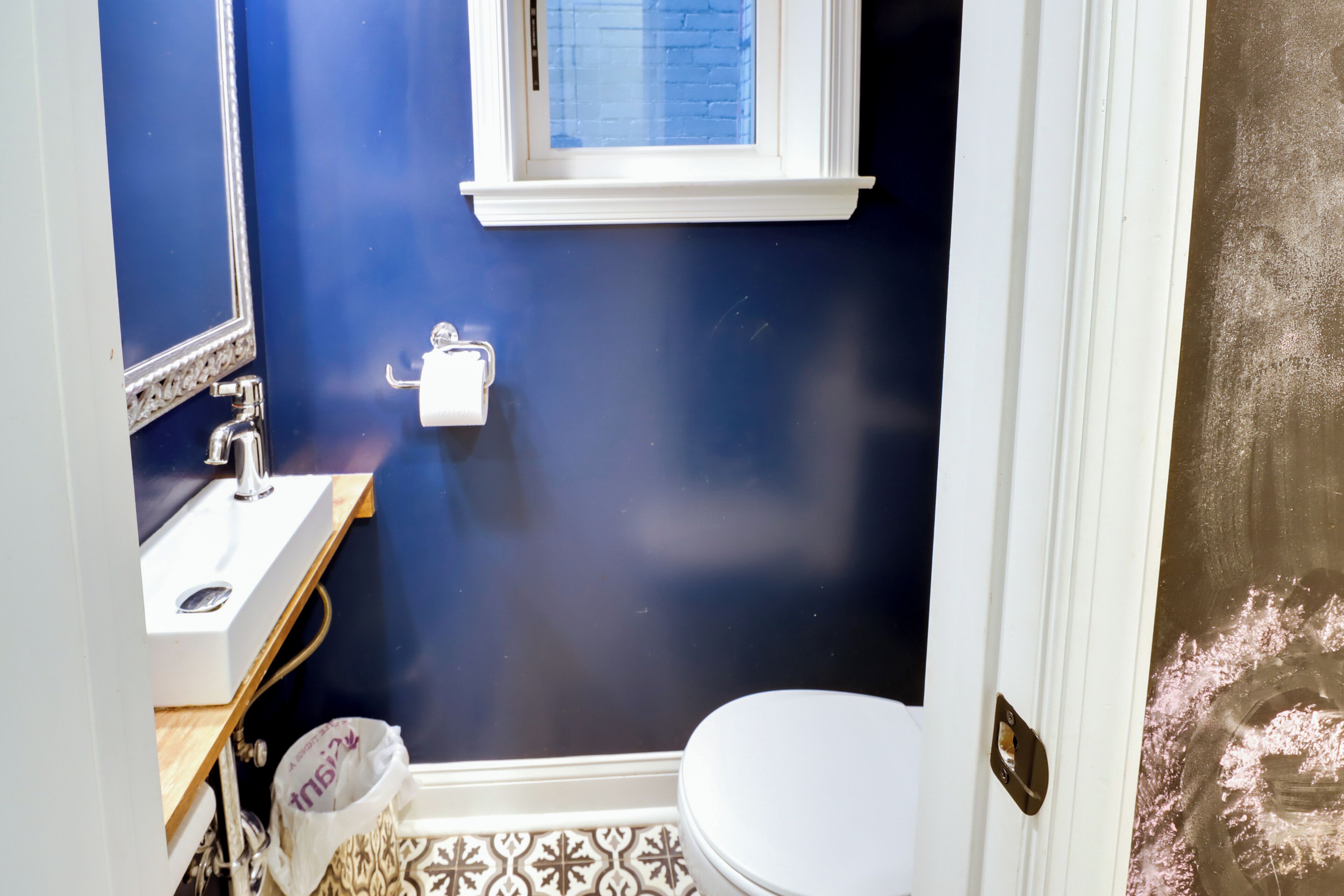 Un baño con inodoro blanco, lavabo y ventana sobre el lavabo.
