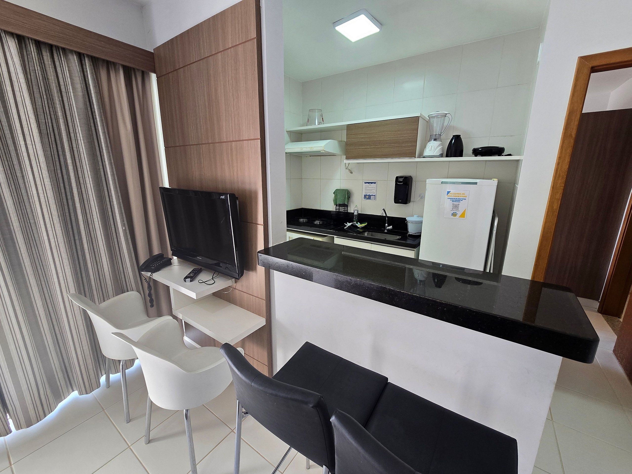 Una cocina moderna con televisión de pantalla plana, refrigerador y cafetera.