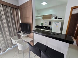 Una cocina moderna con televisión de pantalla plana, refrigerador y cafetera.