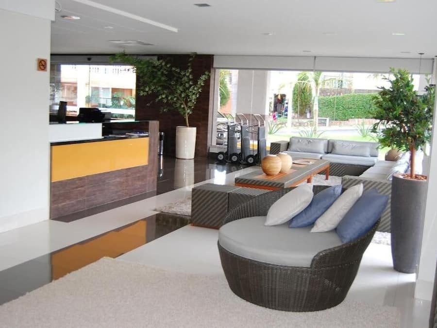 Una moderna hall d'hotel con reception, zona relax e ampie finestre che offrono vista sull'esterno.