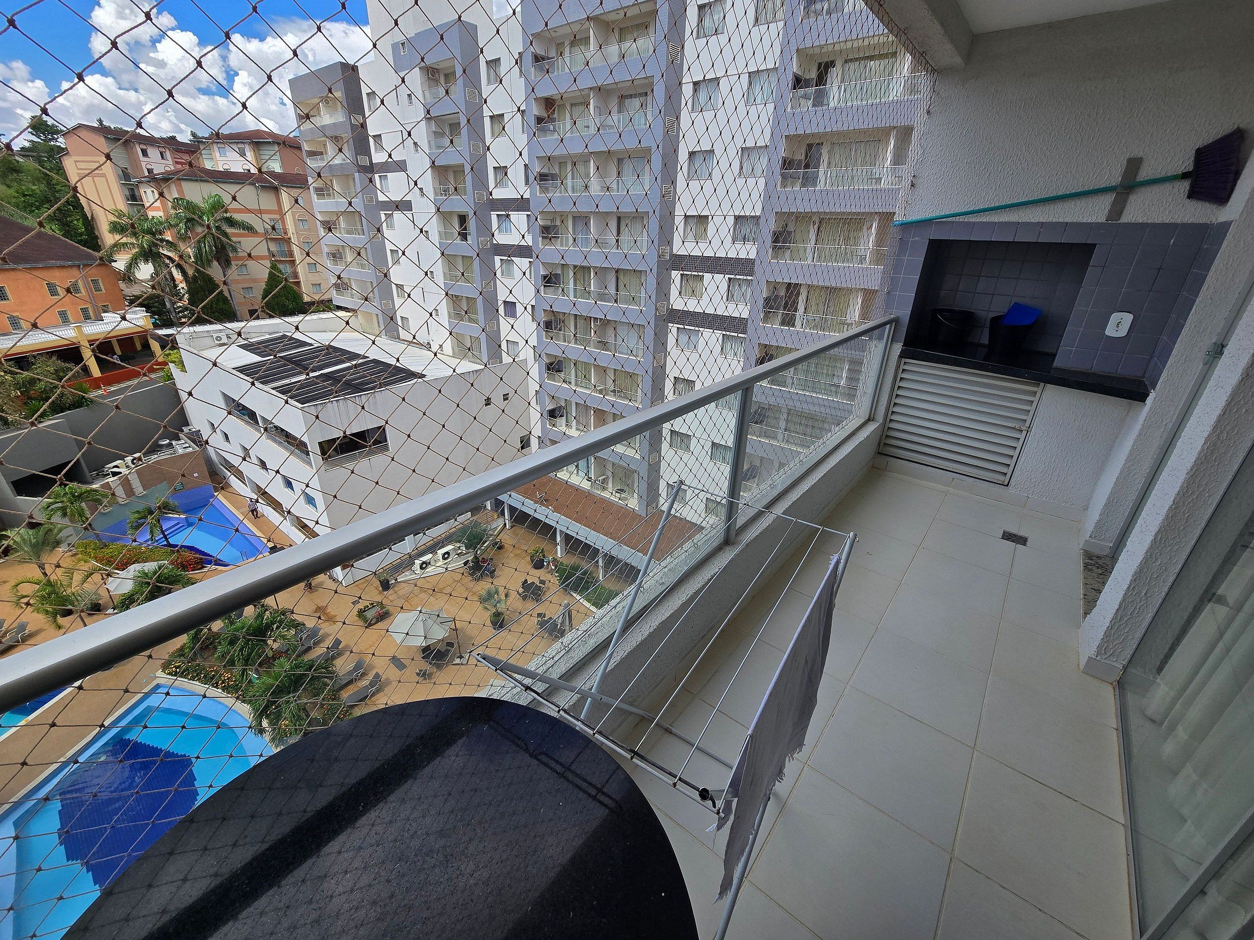 Un edificio residencial de gran altura con varios balcones, piscina y un área exterior techada.