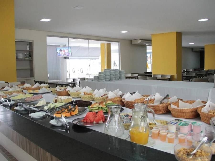 A buffet with various food items and beverages, a television in the background, and a seating area with tables and chairs.