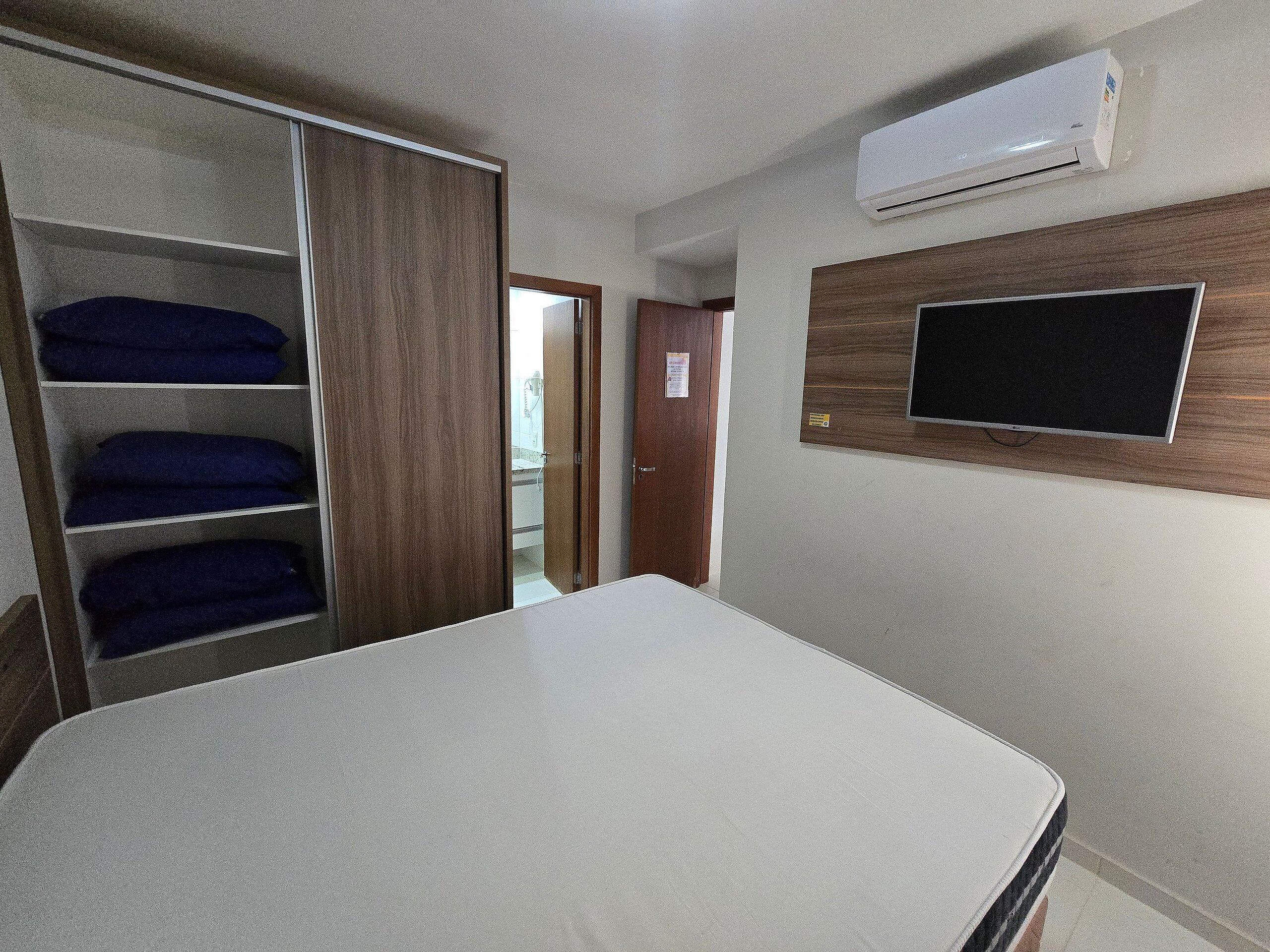 Une chambre équipée d’un lit, d’une armoire, d’un climatiseur et d’un téléviseur.