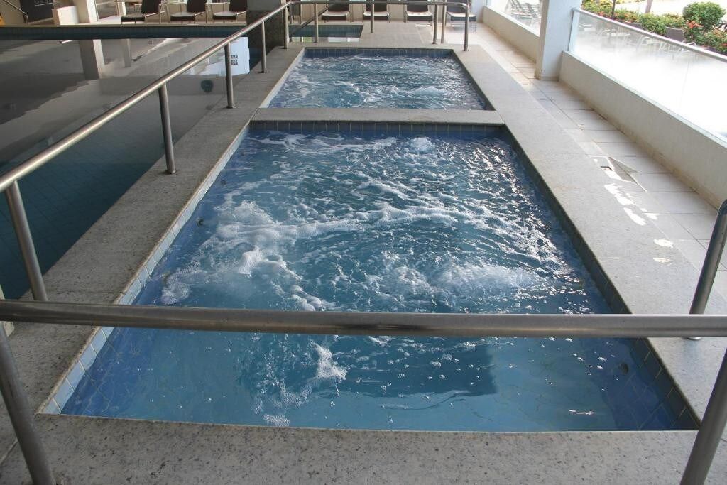 Un espace bien-être comprenant deux bains à remous et un coin salon avec des fauteuils et une table.
