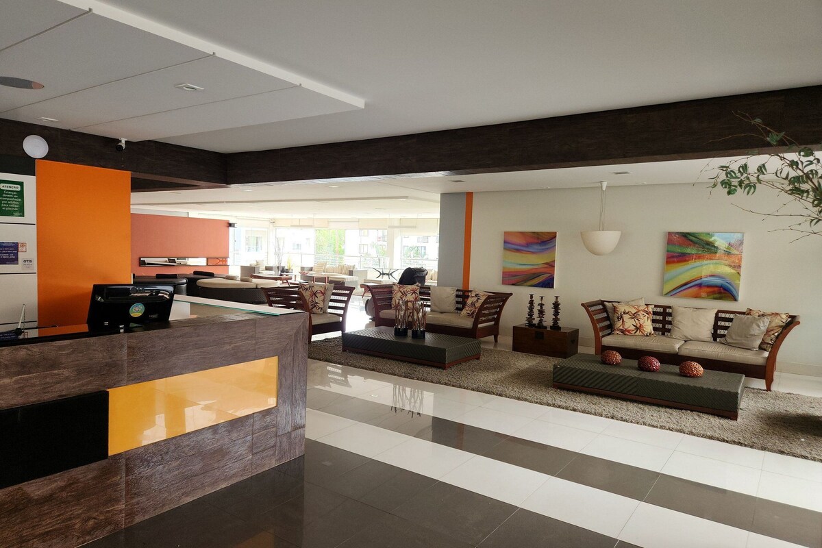 A spacious lobby with a reception desk, seating area, and artwork on the walls.