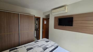 Un dormitorio con cama, armario, aire acondicionado y televisor de pantalla plana.