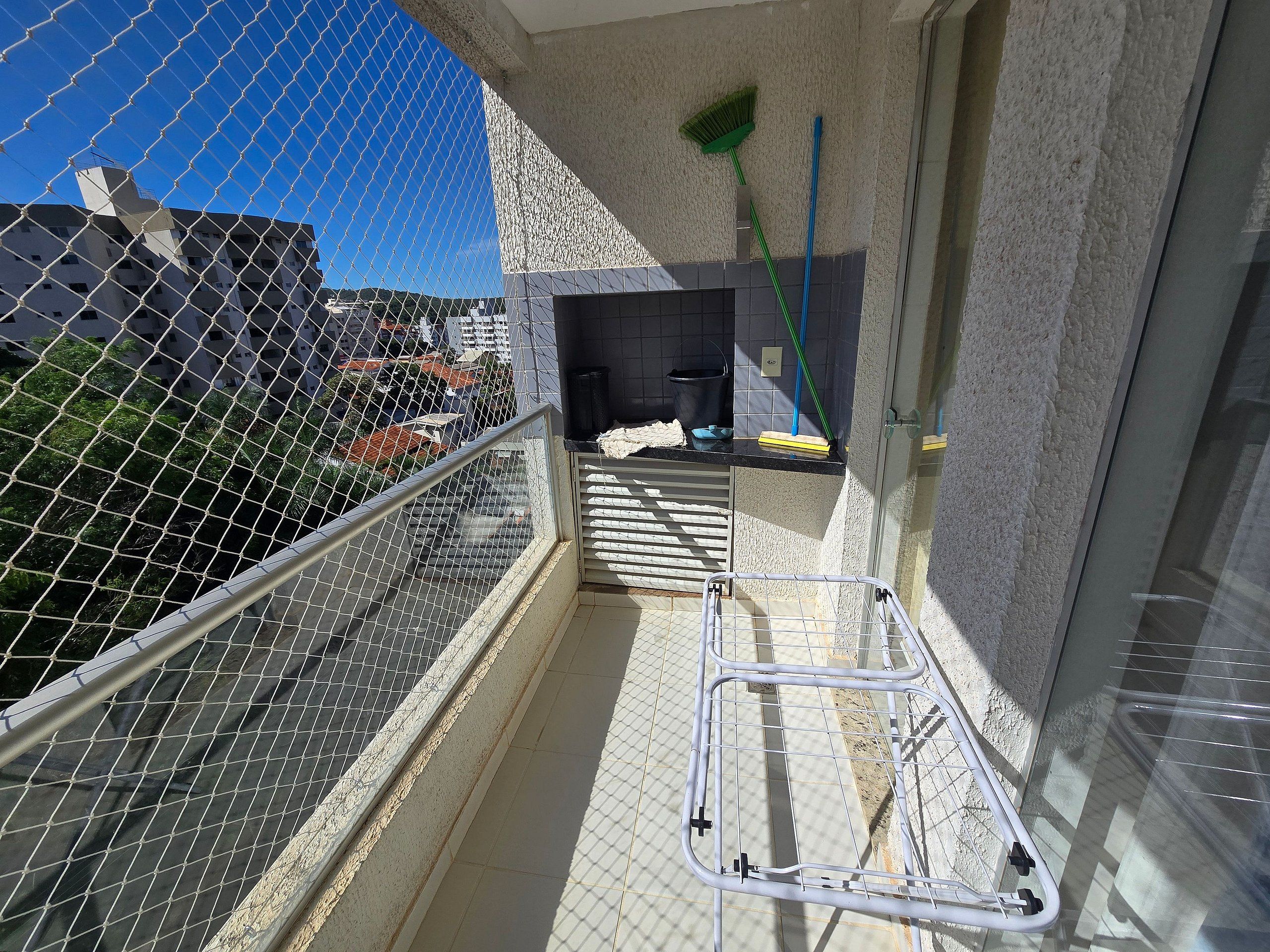 A balcony with a metal railing, a broom, and a mop leaning against the wall.