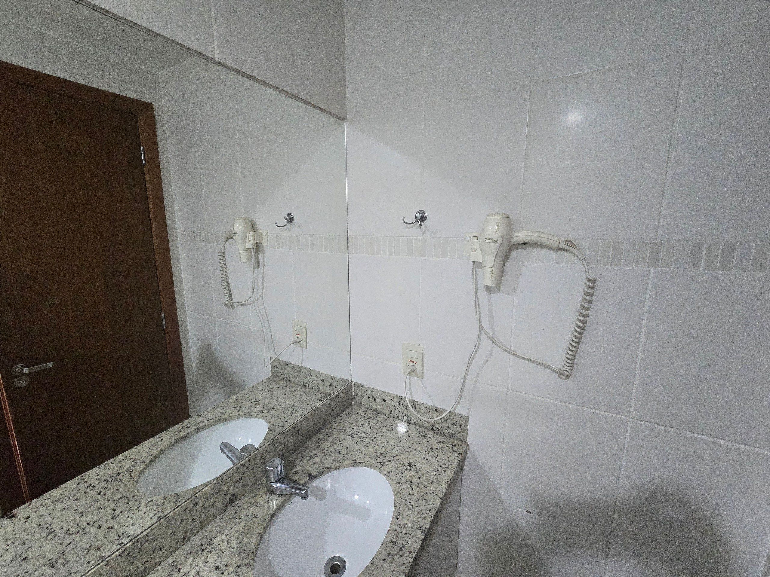 Een badkamer met twee wastafels, een haardroger en een handdoekrek.