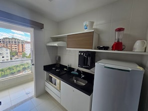 Una cocina moderna con microondas integrado, cafetera y licuadora sobre la encimera.