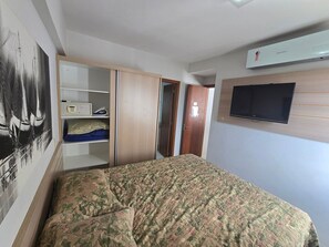 A bedroom with a bed, wardrobe, and a mounted TV. - Aptos Rio Quente - ótima área de lazer (Rio Quente)