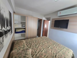 Un dormitorio con cama, armario y televisor montado.