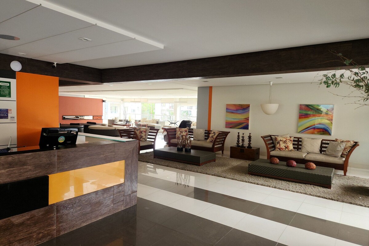 A spacious lobby with a reception desk, seating area, and artwork on the walls.