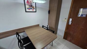 Une pièce avec une table et des chaises en bois, un tableau encadré au mur, un meuble et une porte avec une pancarte.