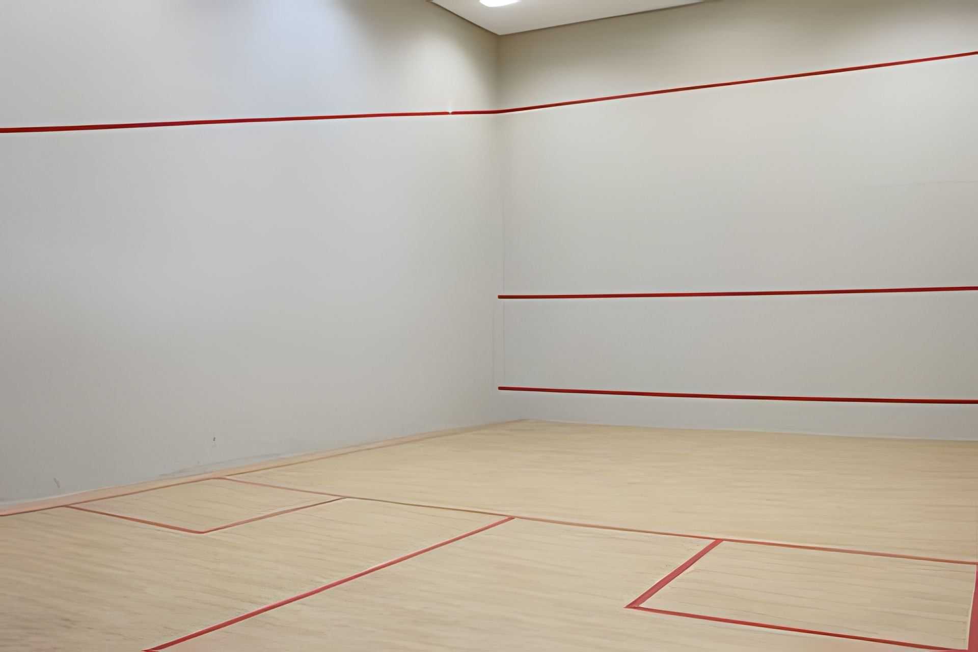 A room with white walls and a wooden floor with red lines marking the boundaries.