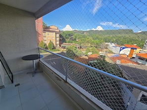 A balcony with a view of a mountainous landscape, a small table, and a chain-link fence. - Aptos Rio Quente - ótima área de lazer (Rio Quente)