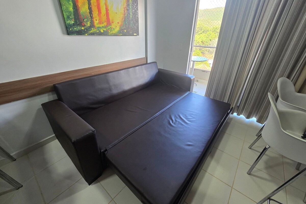 A modern room with a sofa, a chair, and a painting on the wall.