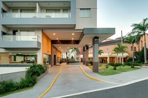 Una entrada de hotel moderna con un paseo techado, zona de estar al aire libre y un jardín bien cuidado.