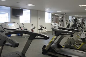 A gym with treadmills, weight machines, and a TV on the wall. - Aptos Rio Quente - ótima área de lazer (Rio Quente)