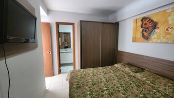 Un dormitorio con cama, televisión, armario y un cuadro en la pared.