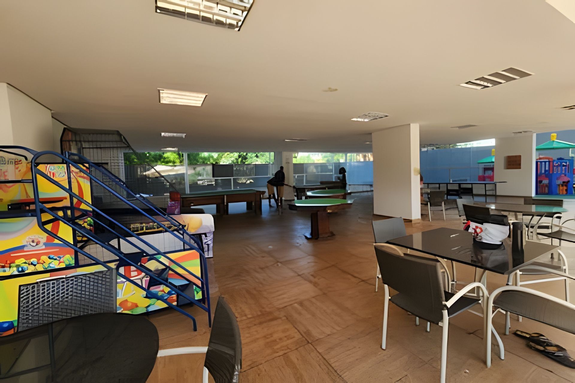Un espacio interior amplio con mesa de billar, mesa de futbolín y zona de comedor con sillas y mesas.