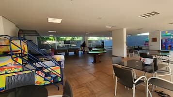 Un espacio interior amplio con mesa de billar, mesa de futbolín y zona de comedor con sillas y mesas.