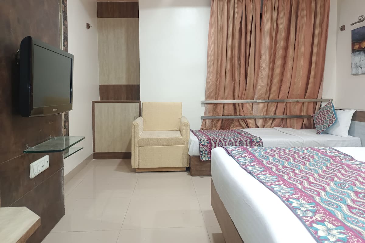 A bedroom with a bed, a chair, a TV, and a curtain.