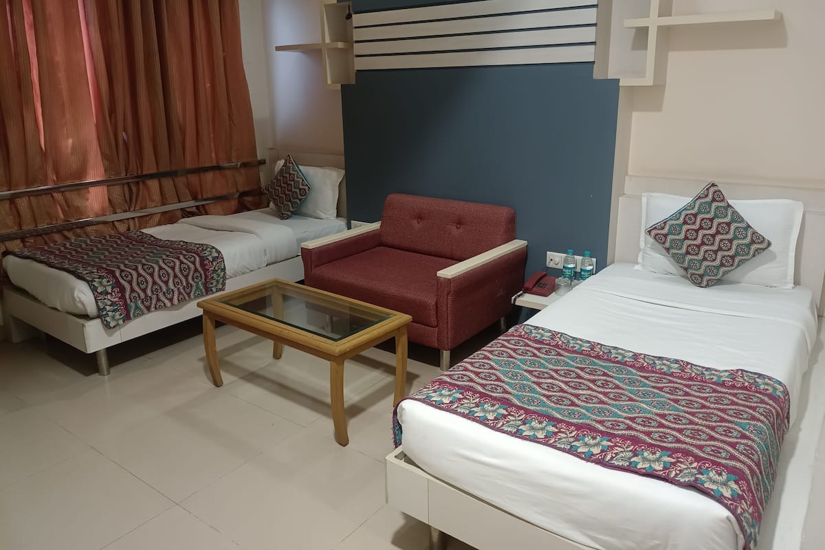 A hotel room with two beds, a sofa, a small table, and a wall-mounted telephone.