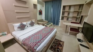 Une chambre d’hôtel avec un lit, une petite table, un téléviseur et une bibliothèque.