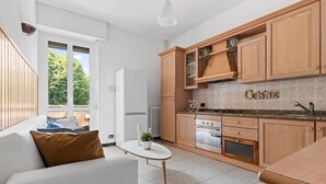 A modern kitchen with wooden cabinets, a built-in oven, and a countertop with a sink. - Two-room Apartment San Siro-fiera Milano M5 Lilac Segesta (Milan)