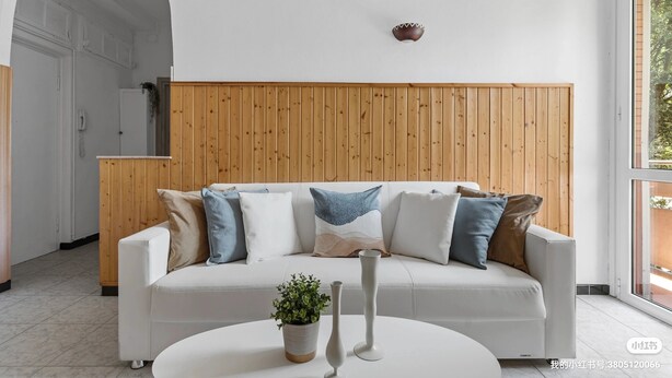 A modern living room with a white sofa, wooden panel wall, and a potted plant on a white table. - Two-room Apartment San Siro-fiera Milano M5 Lilac Segesta (Milan)