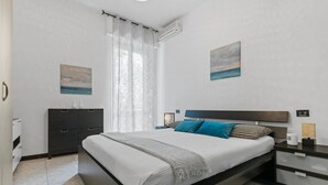 A modern bedroom with a bed, a nightstand, a dresser, and two paintings on the wall. - Two-room Apartment San Siro-fiera Milano M5 Lilac Segesta (Milan)