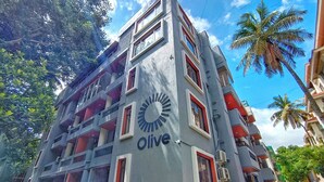Un edifici amb el nom 'Olive' a la façana, que té diversos balcons i aires condicionats.