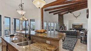 A spacious kitchen with granite countertops, a central island, and a stone fireplace. - Casa Verde 4 Bedroom Home by RedAwning (Scottsdale)