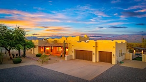 A desert-style house with a large garage, a patio with a cactus, and a view of mountains in the background. - Casa Verde 4 Bedroom Home by RedAwning (Scottsdale)