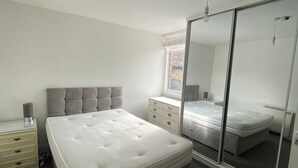 A bedroom with a large bed, a dresser, a mirror, and a window. - Apartment - Sleeps 2 & Great Transport Links (London)