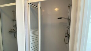 A bathroom with a white sink, a mirror, and a glass-enclosed shower area. - Apartment - Sleeps 2 & Great Transport Links (London)