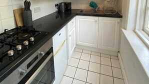 A kitchen with white cabinets, a black countertop, and a gas stove. - Apartment - Sleeps 2 & Great Transport Links (London)