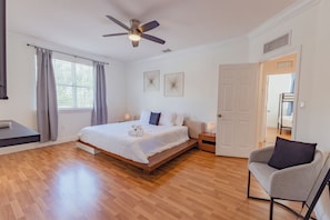 A bedroom with a bed, a chair, a ceiling fan, and a door leading to another room. - Miami Getaway Heated Pool House & Pool Table Villa (Miami)