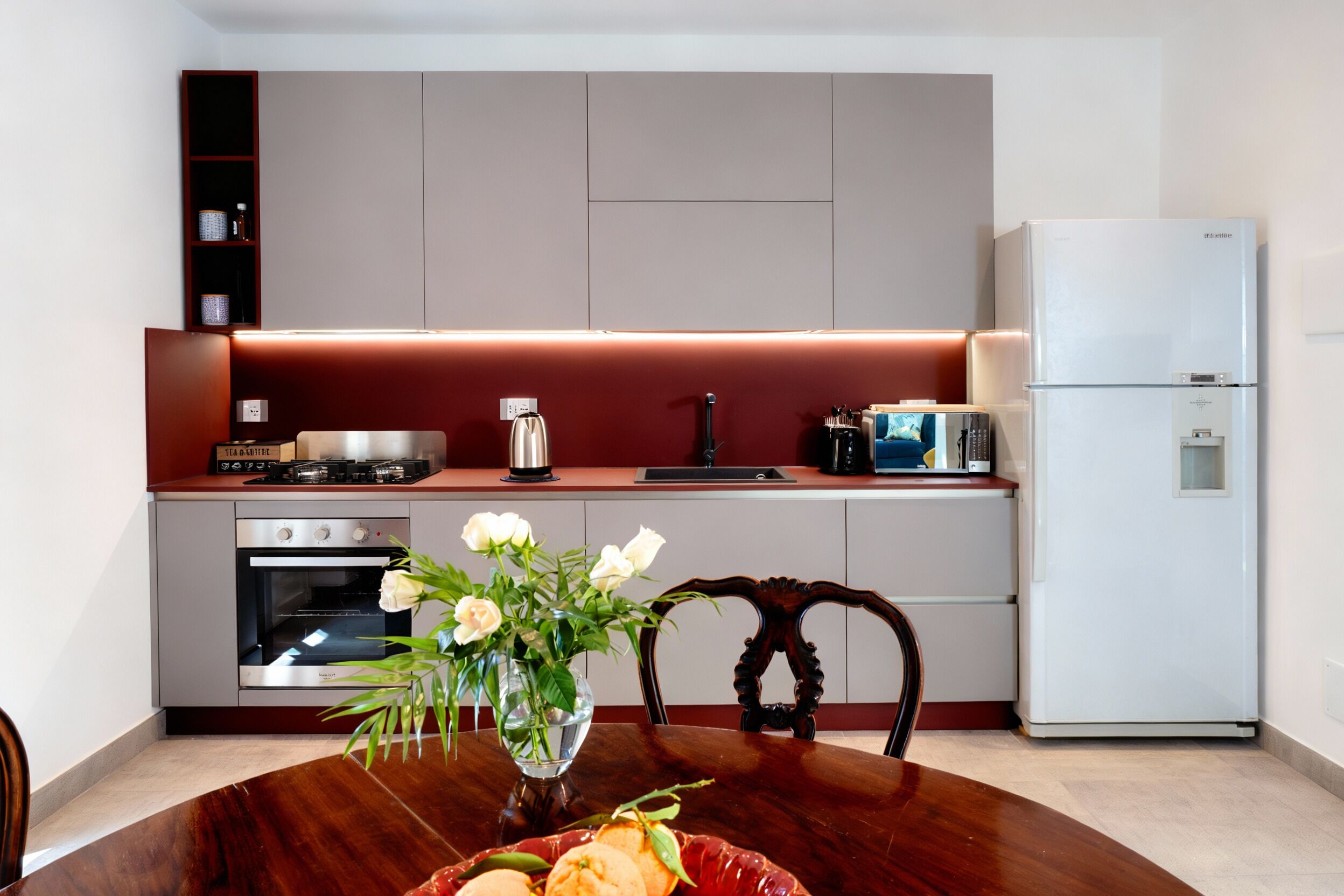 Una cocina moderna con una mesa de comedor, un florero y un refrigerador.