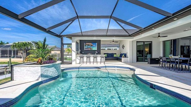 A swimming pool with a covered patio area, a bar, and a view of the backyard.