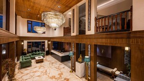 A spacious lobby with a high ceiling, a grand chandelier, and a marble floor. There are seating areas with sofas and a reception desk. - Udaan Hotel Pine Crest (Gyalshing)